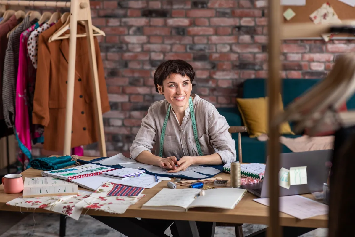 Happy seamstress happy sitting with design on the table