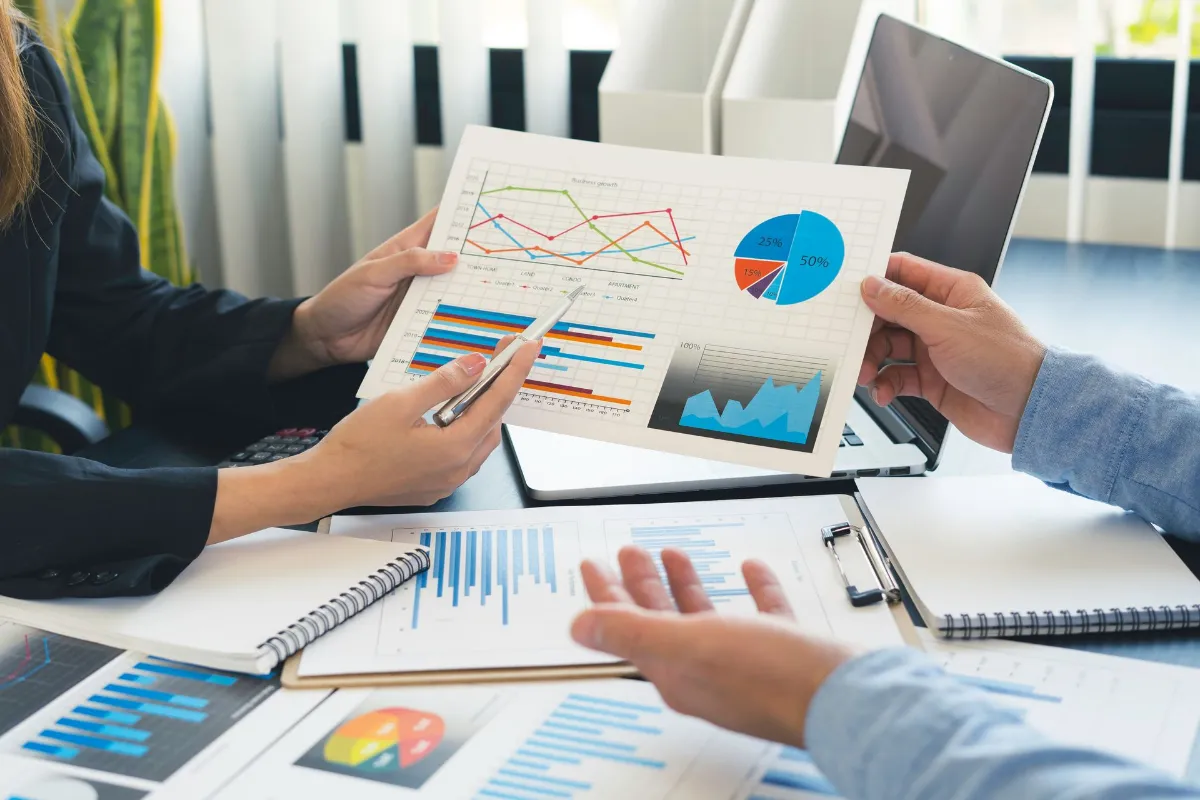 Finance business people or accountants point to the graph to describe the company's income, expenses, taxes